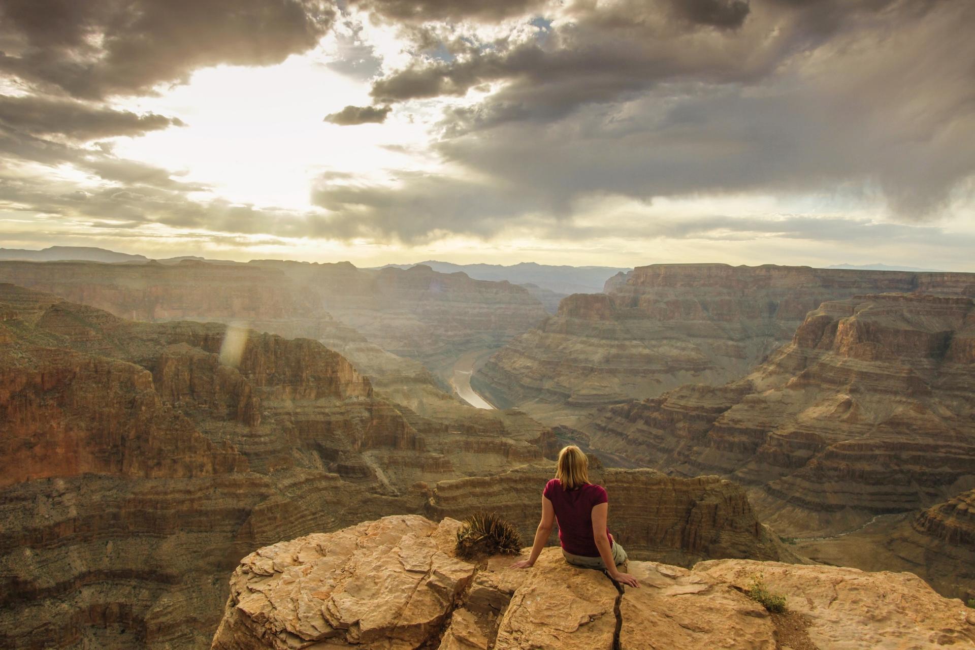 A woman sits on the rim looking into the canyon