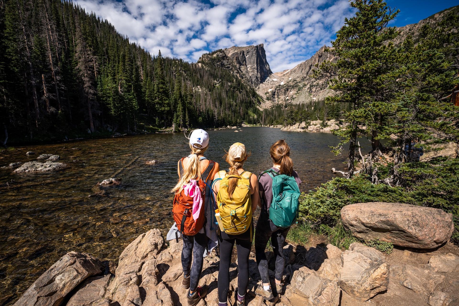 Three hikers overlooking Dream Lake and the mountains beyond